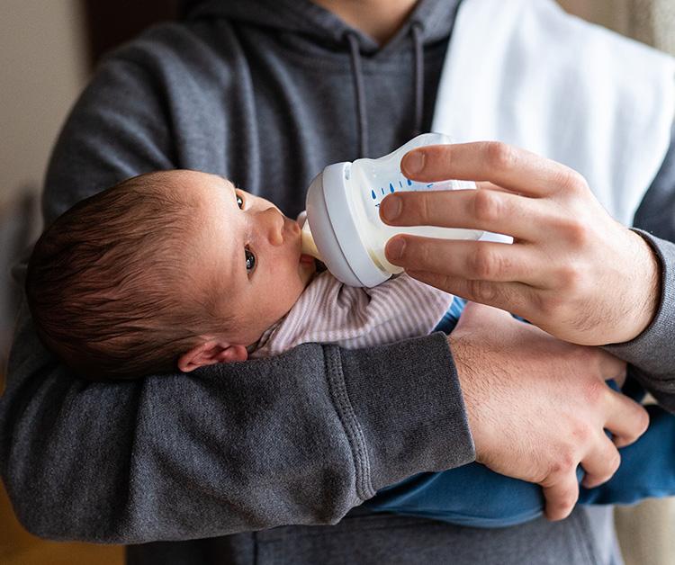 Dad bottle feeding newborn