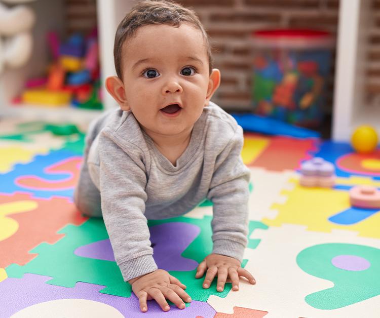 Baby crawling on multi-colored puzzle mat