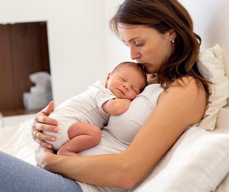 Mom sitting and holding her newborn against her chest