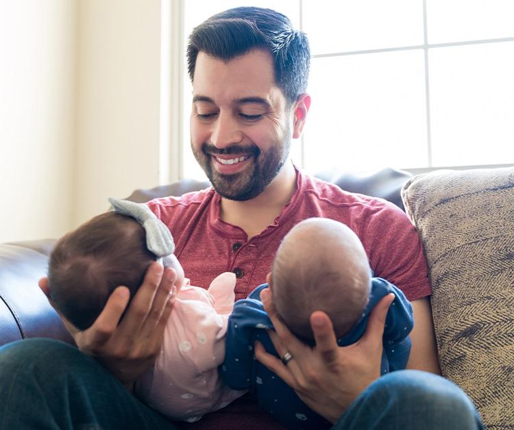 Dad holding his twins and smiling