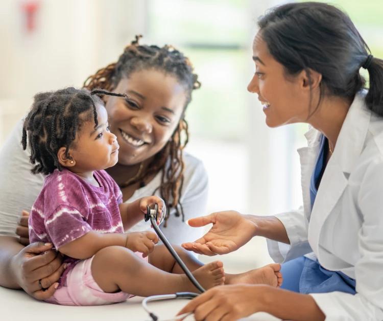 Mom and nurse smiling at baby in pediatrician's office