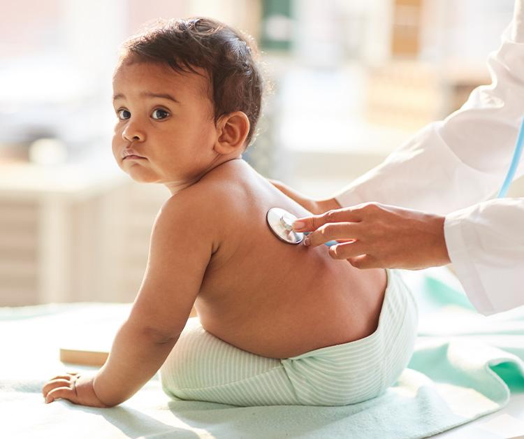 Doctor holding stethoscope to babys back