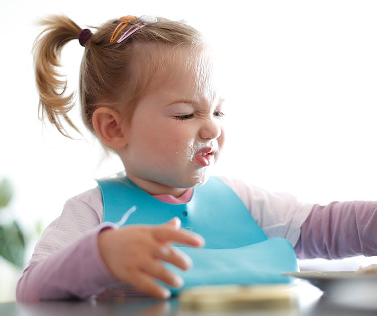 Toddler girl eating and making a face