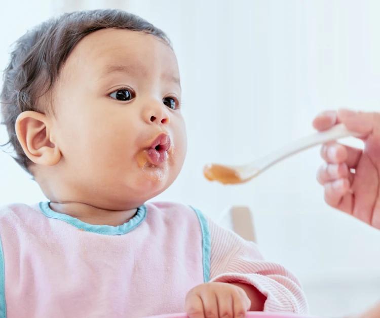 Bebé comiendo alimentos sólidos con cuchara