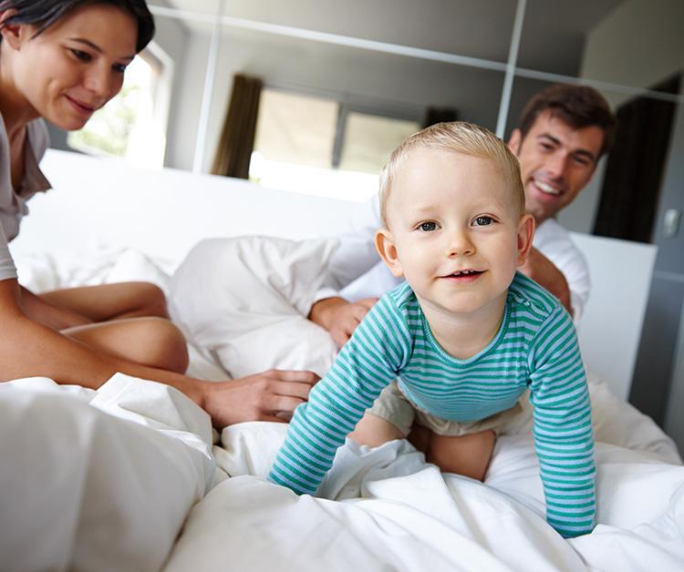 Niño jugando en la cama con su mamá y su papá