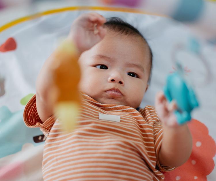 Baby playing with toy ring while laying on the floor