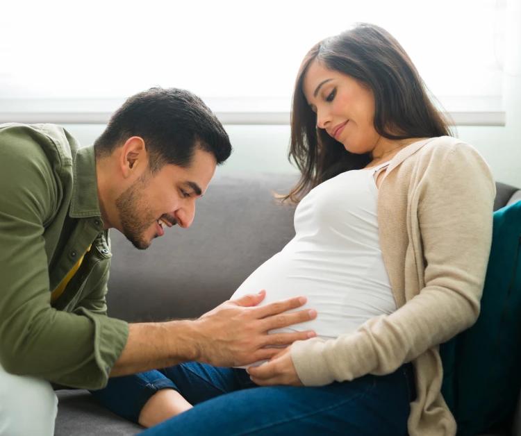 Una mujer embarazada hablando con su esposo.