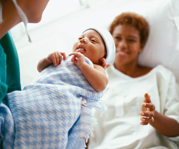 Nurse handing baby to new mom