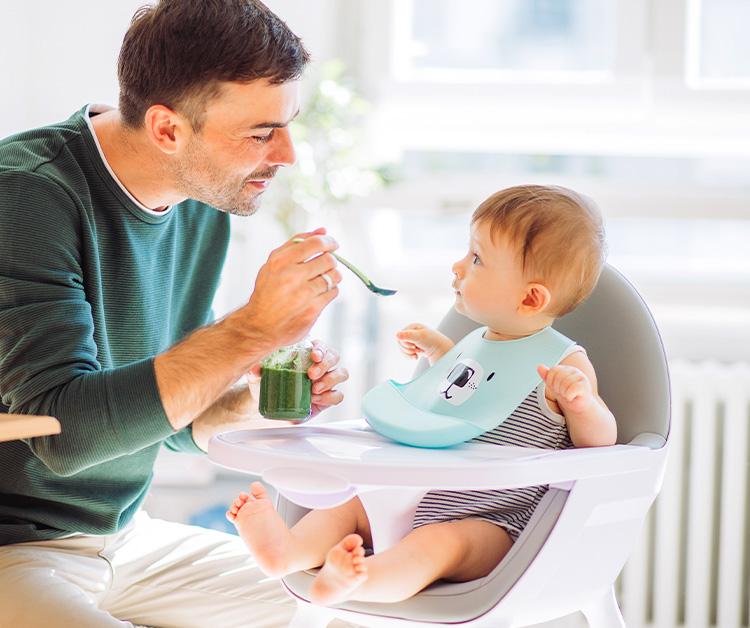 Dad feeding baby in high chair