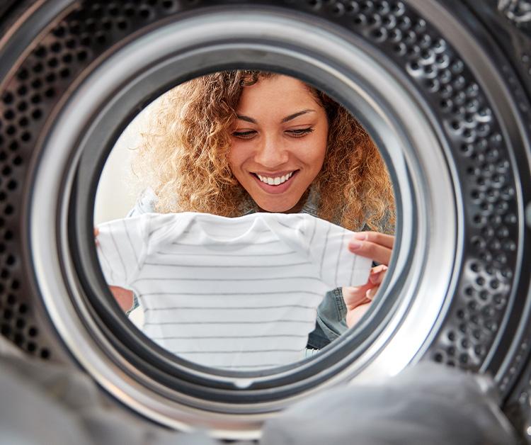 Smiling woman putting a onesie in the washer