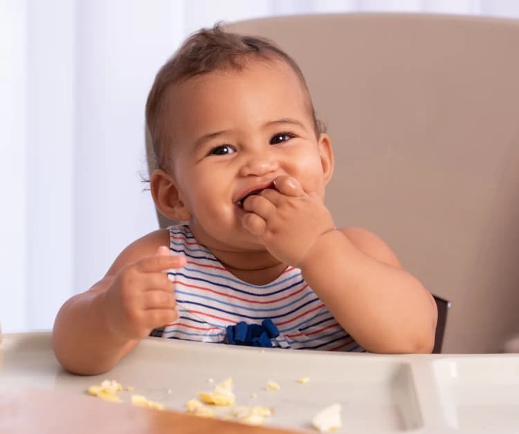 Baby eating eggs in a high chair