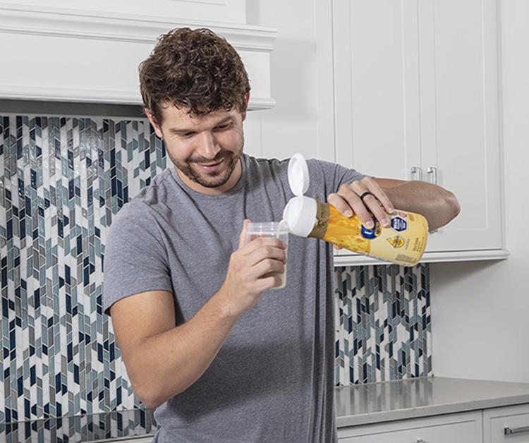 Dad in the kitchen pouring liquid formula into a bottle