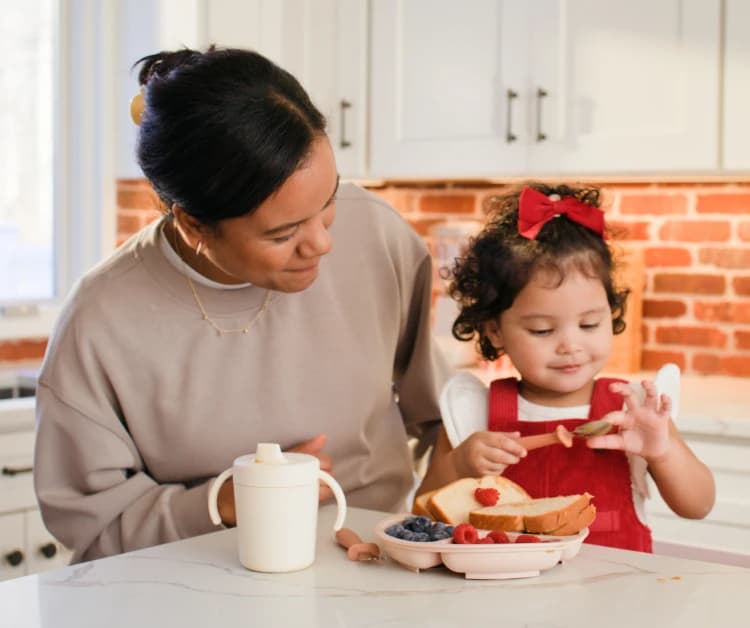 Mom sitting at counter with toddler eating