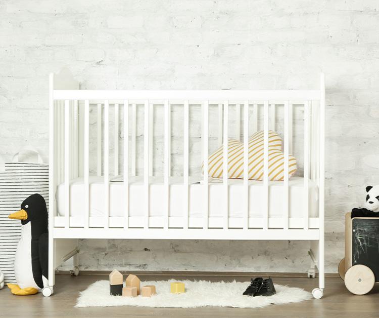 A white crib with a fluffy rug in front of it