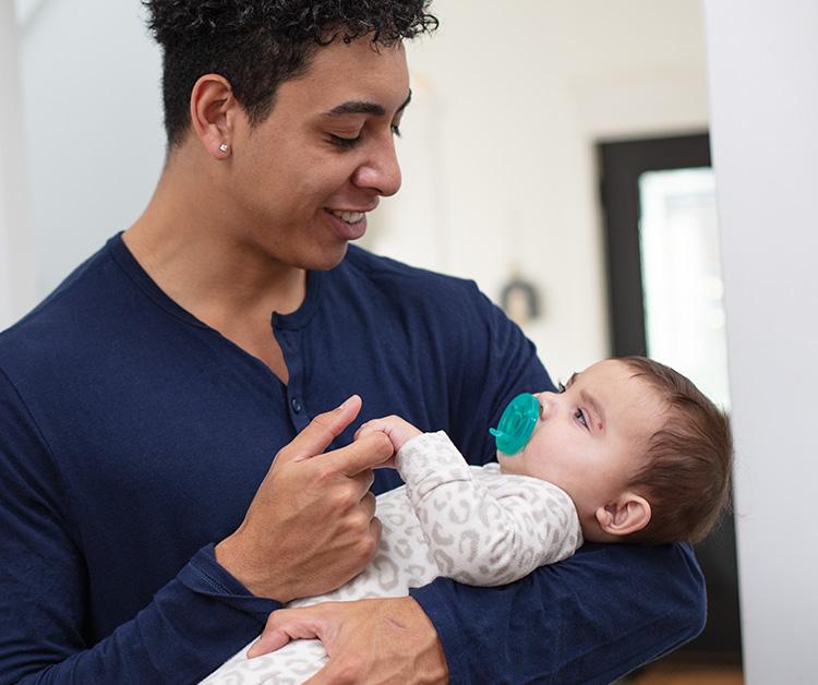 Dad cradling baby and holding baby's hand